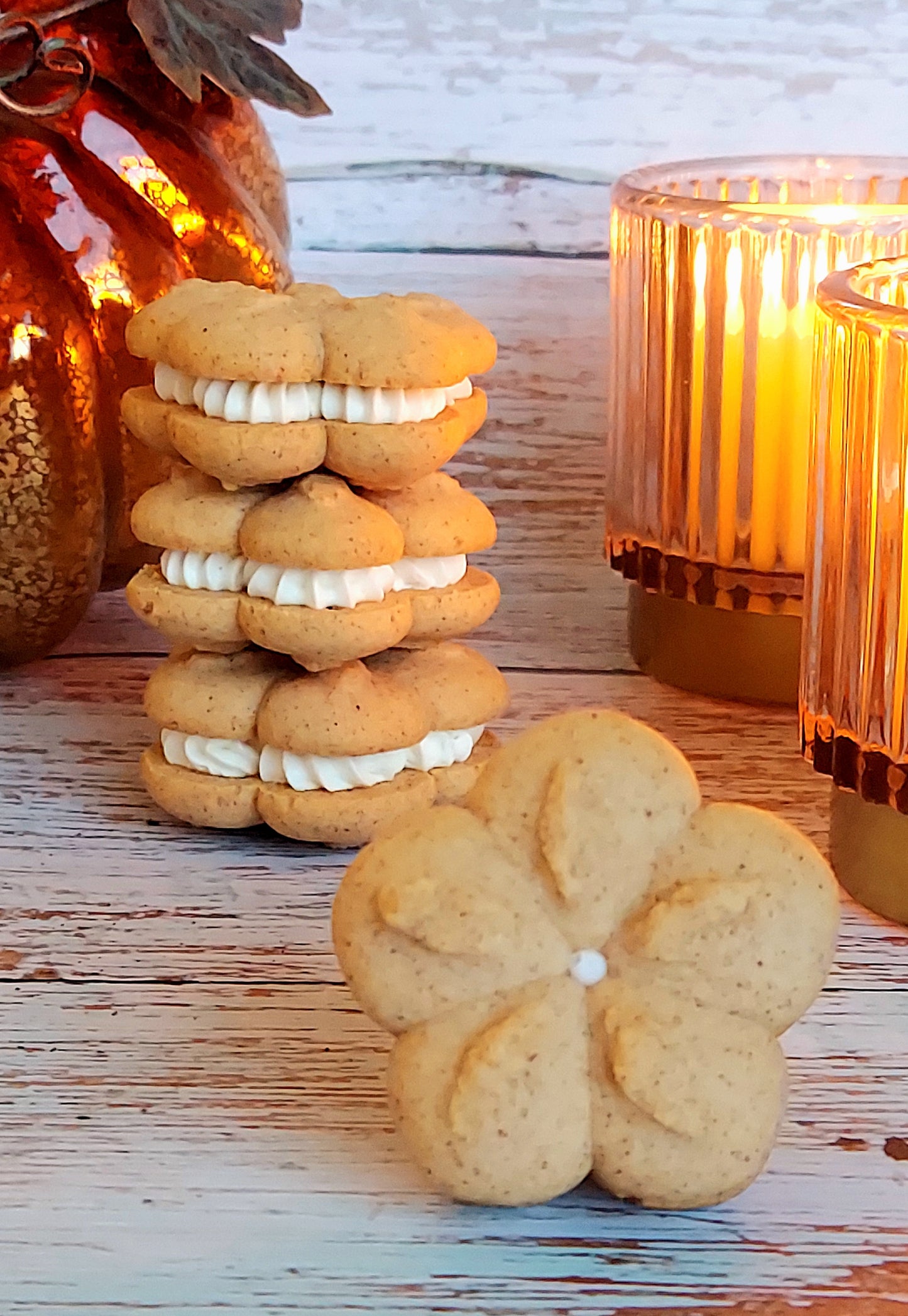 Stack of sandwich cookies with cream filling on a wooden surface with candles in the background