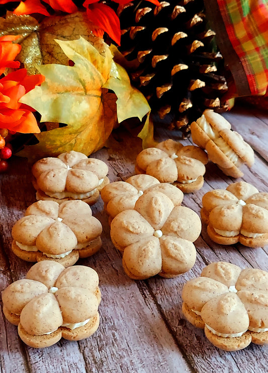 Pumpkin-shaped cookies on a wooden surface with autumn decorations.